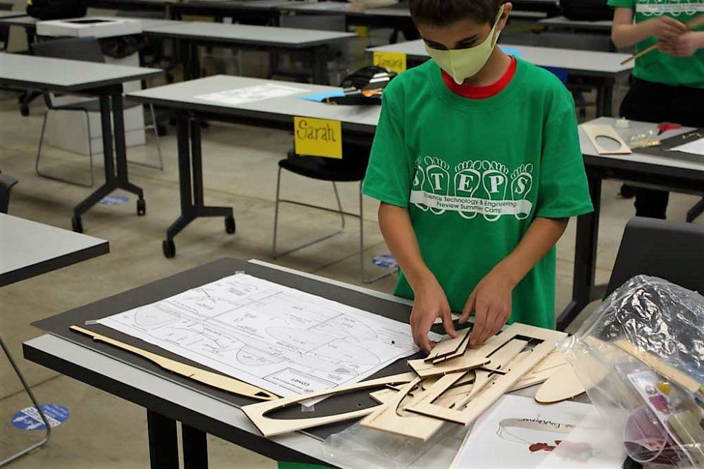 A camper begins making his wooden airplane